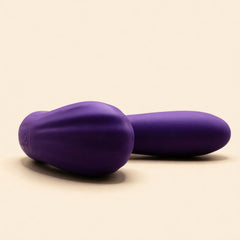 Sucking Sweet in purple silicone lying flat, seen end-on, on a cream ground